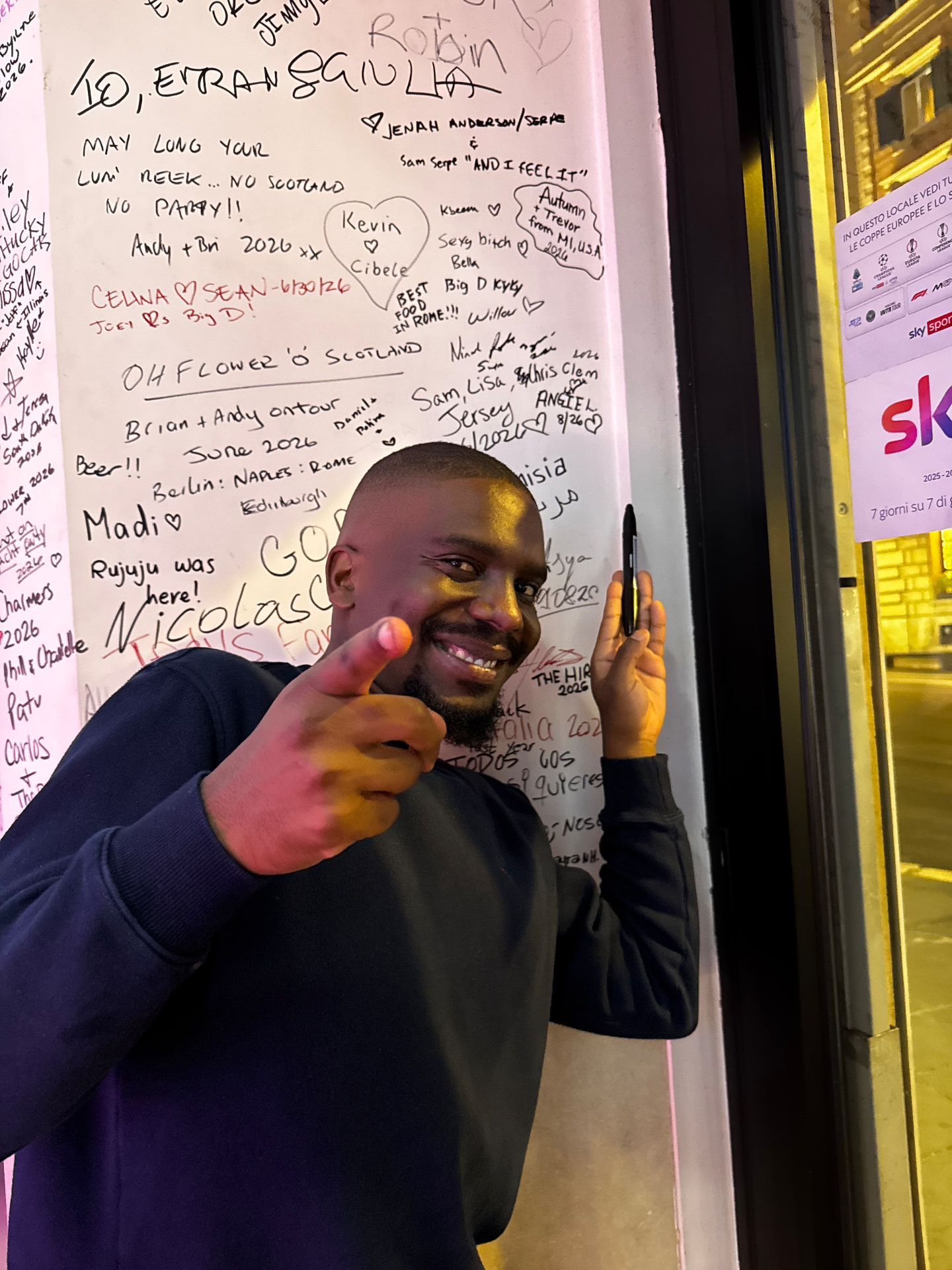 A guest pointing at the camera after signing the wall at Miami Pub Roma