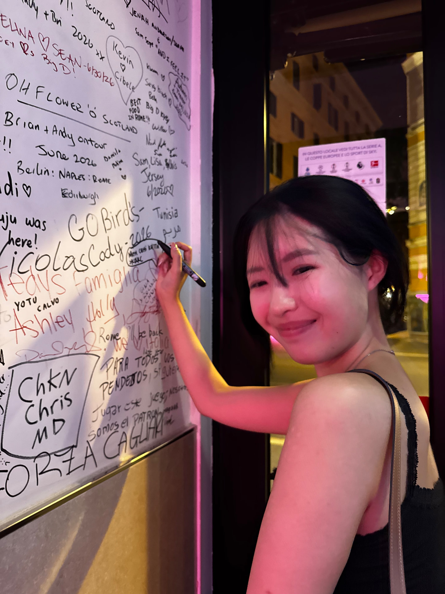 A guest writing her name on the traveller wall by the entrance
