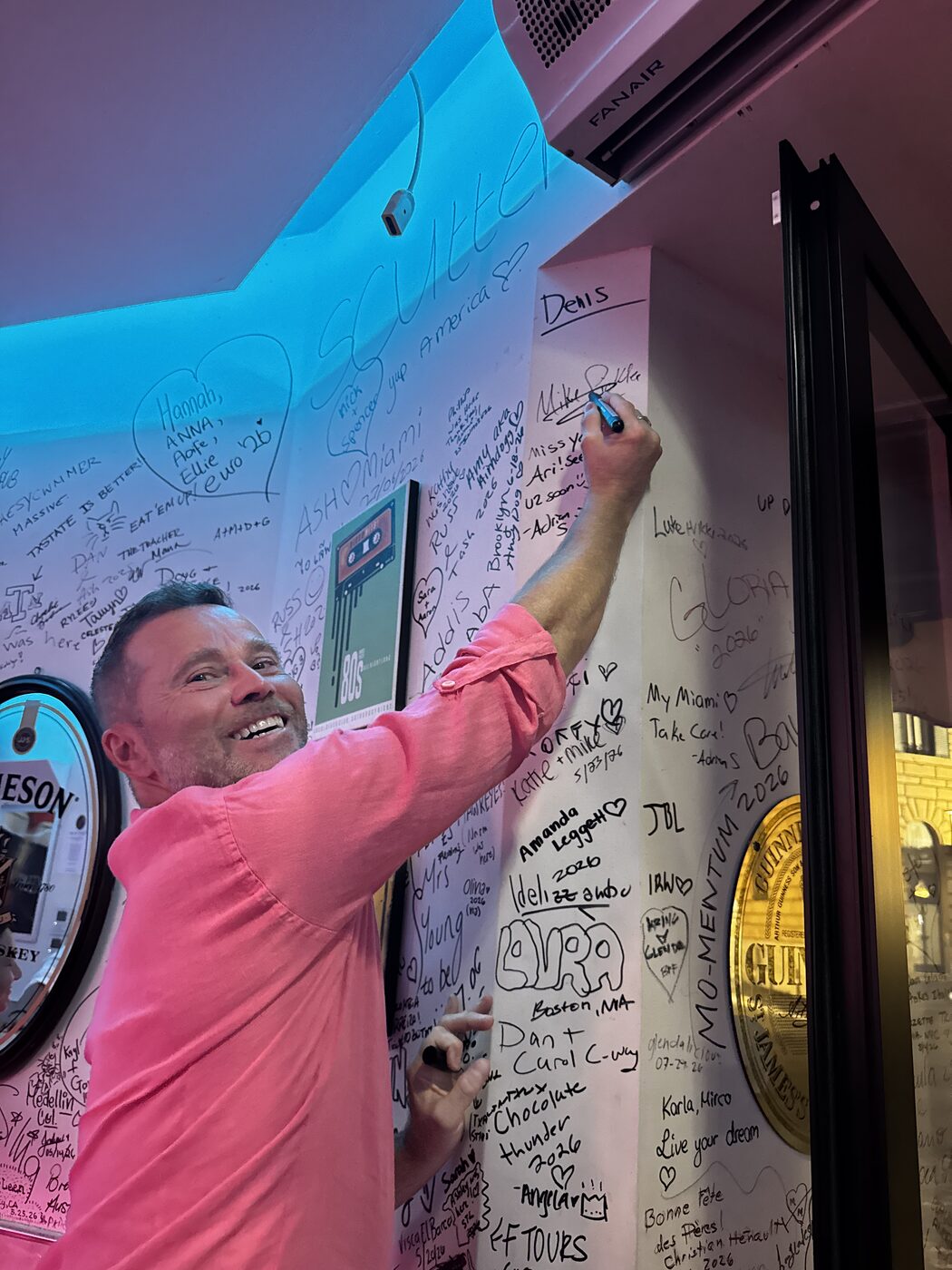 Handwritten signatures and messages covering the wall at Miami Pub Roma