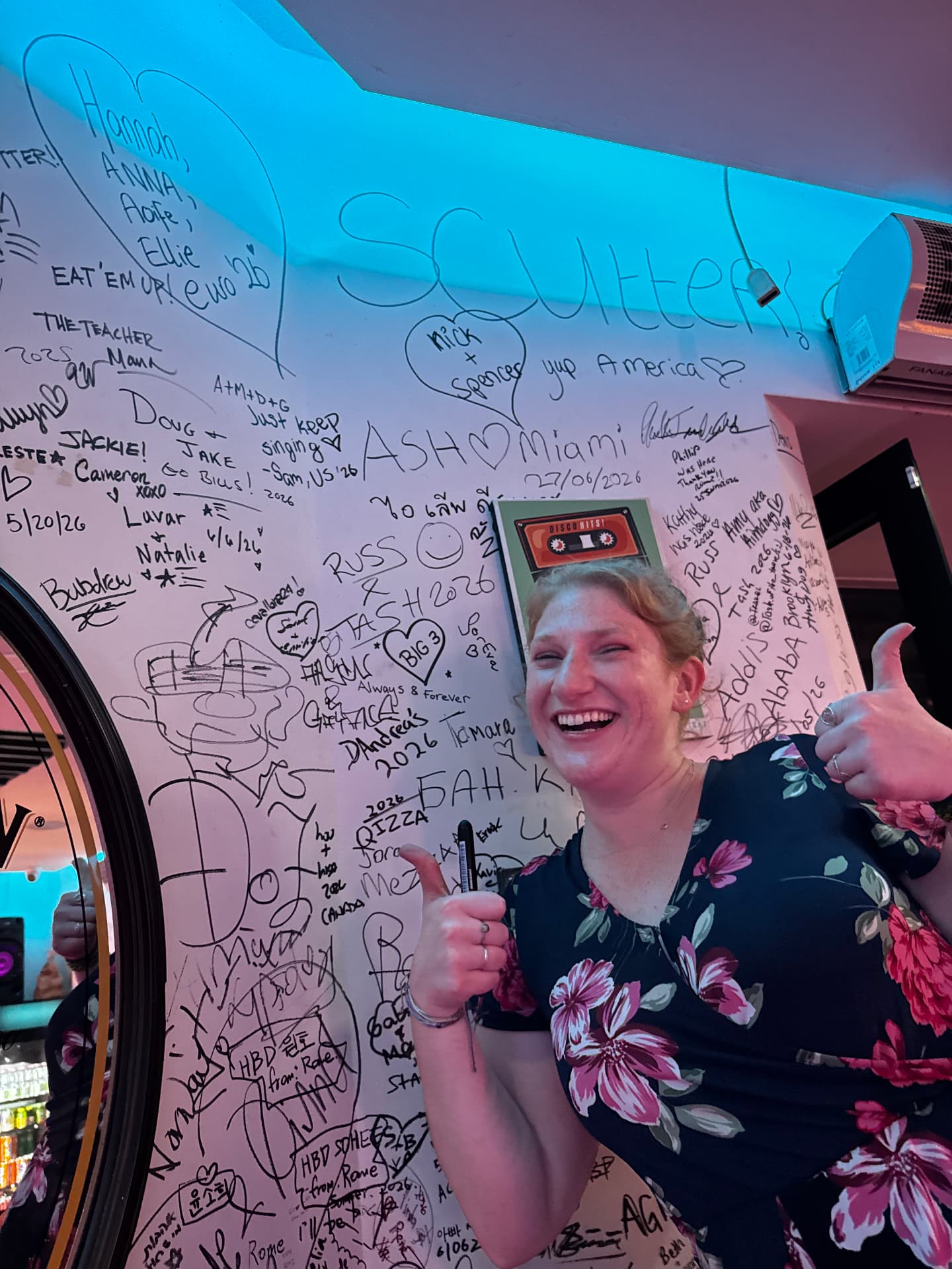 A smiling guest giving a thumbs up beside the signatures she just added
