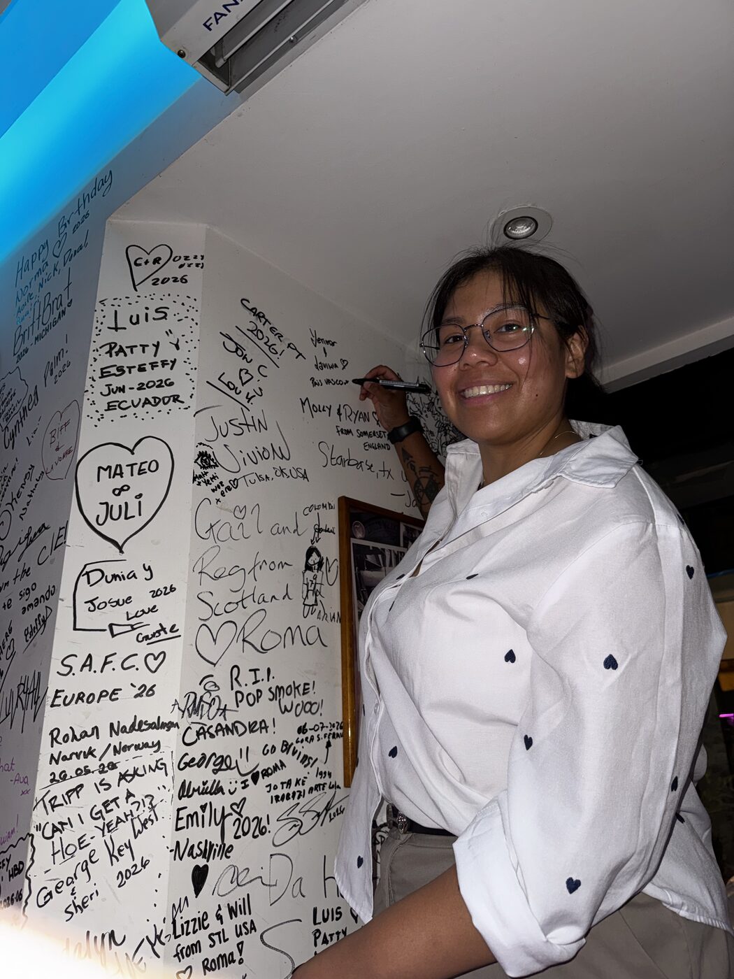 A guest signing her name on the traveller wall at Miami Pub Roma